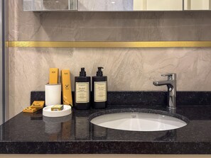 A bathroom with a marble countertop, a sink, and toiletries including bottles and a soap dish. - Qoople Elize B26 - Cozy 1-bedroom apartment in gorgeous Alanya (Alanya)