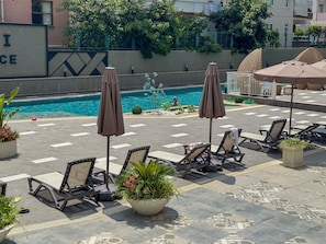 A poolside area with lounge chairs, umbrellas, and potted plants. - Qoople Elize B26 - Cozy 1-bedroom apartment in gorgeous Alanya (Alanya)