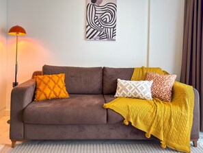 Ein braunes Sofa mit einer gelben Decke und gemusterten Kissen.