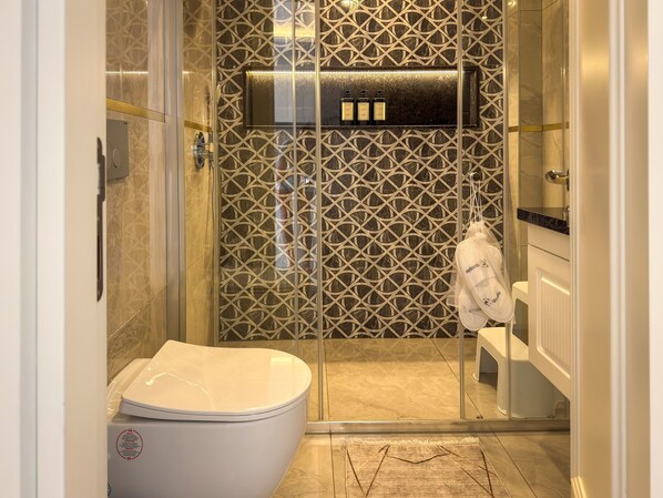 A modern bathroom with a glass shower enclosure, a toilet, and a vanity with a marble countertop. - Qoople Elize B26 - Cozy 1-bedroom apartment in gorgeous Alanya (Alanya)