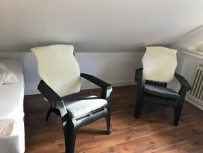 Two chairs with white cushions in a room with wooden flooring and a white radiator. - Wohnen am Wanderweg II (Aurich)