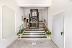 A staircase leading to an upper floor with a metal railing, a door on the right, and potted plants at the bottom. - Mirea Domus - Salerno - Train Station/Bus/Ferry to Amalfi, 5 minutes away (Salerno)