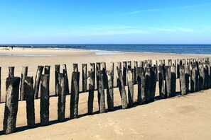 A beach with a wooden fence in the foreground and a pier in the background. - AK13 Holiday home near Domburg (Aagtekerke)