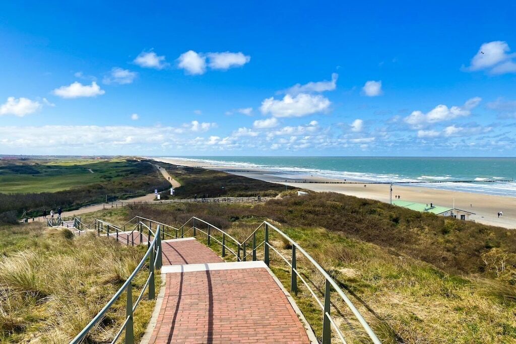 A coastal walkway leading to a beach with a clear sky.