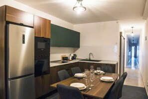A modern kitchen with a built-in oven, microwave, and refrigerator. There is a dining table set with plates and glasses. - Modern & Comfortable Apartment in Central Msida (L-Imsida)