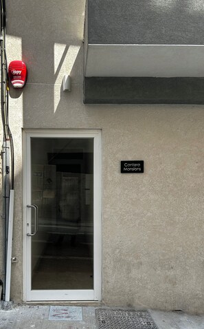 A building entrance with a glass door, a fire alarm, and a sign indicating 'Canteira Mansions'. - Modern & Comfortable Apartment in Central Msida (L-Imsida)