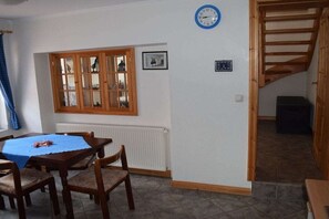 A dining area with a table and chairs, a window with a view, a clock, and a staircase. - with sauna and fireplace (Tönning)