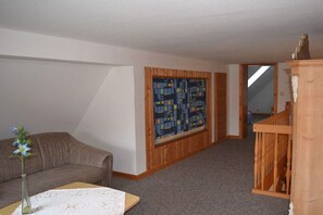 A room with a brown sofa, a small table with a vase, a wooden cabinet, and a large abstract painting on the wall. - with sauna and fireplace (Tönning)