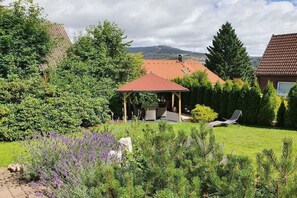 Un jardin avec un kiosque, une pelouse et une chaise.