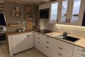A modern kitchen with white cabinetry, a black induction cooktop, and a stainless steel sink. - Holiday apartment with 2 bedrooms (Braunlage)