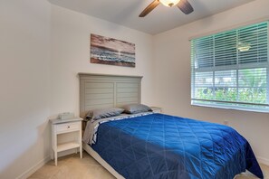 A bedroom with a bed, nightstand, ceiling fan, window with blinds, and a wall-mounted painting. - Punta Gorda Resort Condo: Pool Access, Lanai (Punta Gorda)