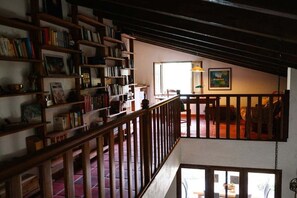 Ein mehrstöckiger Raum mit einer Holztreppe, Bücherregalen, einem Essbereich und einem Gemälde an der Wand.