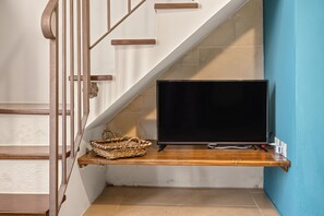 Un escalier avec un téléviseur à écran plat fixé sur une étagère en bois, un panier en osier et une prise de courant.