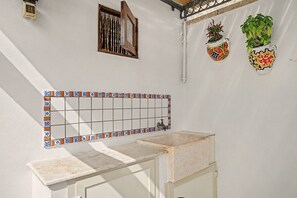 Un baño con pared de azulejos, una ventana con marco de madera y un lavabo con encimera de mármol.