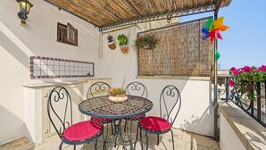 A covered outdoor seating area with a round table and four chairs, a decorative wall with hanging planters, and a bamboo ceiling. - 'La Casetta di Viola' charming and unique cottage just a few km from the sea! (Palmariggi)