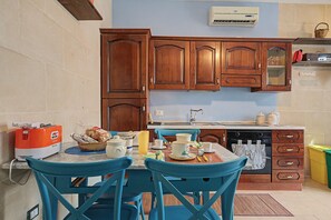 A kitchen with wooden cabinets, a dining table with chairs, a toaster, and a basket of bread.
