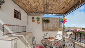 A covered outdoor seating area with a table and chairs, a hanging plant, and a decorative pinwheel. - 'La Casetta di Viola' charming and unique cottage just a few km from the sea! (Palmariggi)