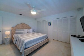 Ein Schlafzimmer mit einem Bett, einem Deckenventilator, einer Nachttischlampe und einem Kleiderschrank.