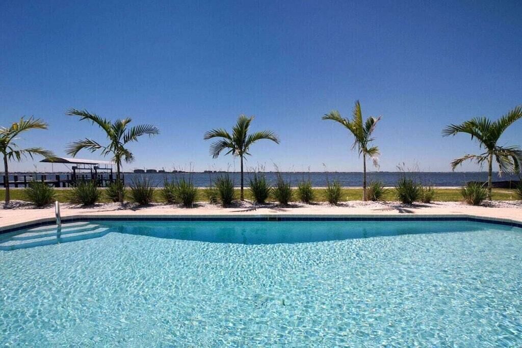 Une piscine d’eau cristalline, d’un bleu éclatant, avec vue sur la mer et les palmiers.