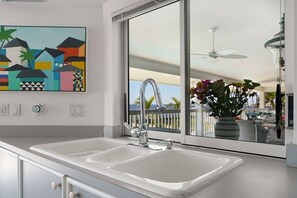 Eine moderne Küche mit einem großen Fenster, einem Deckenventilator und Blick ins Freie.