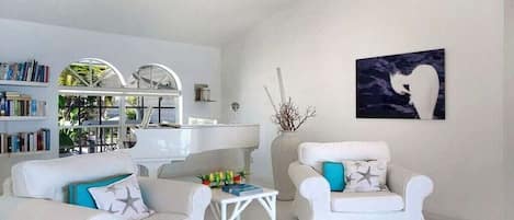 Una sala de estar moderna con muebles blancos, una estantería y un cuadro en la pared.