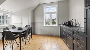 Eine moderne Küche mit Essbereich, Holzboden und Blick auf Gebäude durch das Fenster.