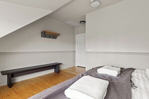 A bedroom with a sloped ceiling, a bench, a bed with towels, and a door. - Best View in Downtown Reykjavik!  3 Bedrooms + 3 Ensuite-Bathrooms (Reykjavík)