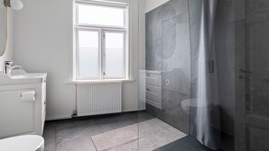 Ein Badezimmer mit Toilette, Waschbecken, Fenster und Duschbereich.