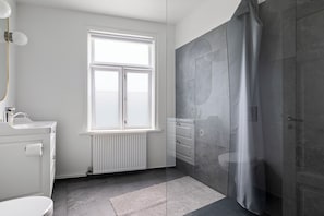 A bathroom with a toilet, sink, window, and shower area. - Best View in Downtown Reykjavik! 3 Bedrooms + 3 Ensuite-Bathrooms (Reykjavík)