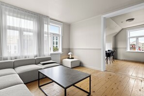 A modern living room with a sectional sofa, a small table, and a dining area with chairs. - Best View in Downtown Reykjavik! 3 Bedrooms + 3 Ensuite-Bathrooms (Reykjavík)