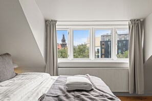 A bedroom with a large window, a bed, and a radiator. - Best View in Downtown Reykjavik! 3 Bedrooms + 3 Ensuite-Bathrooms (Reykjavík)