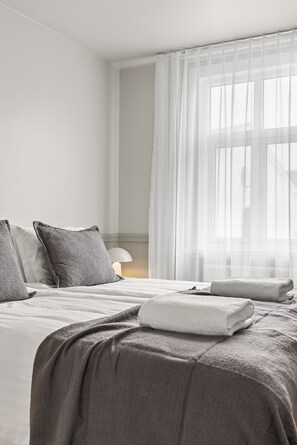 A hotel room with a bed, pillows, a bedside lamp, and sheer curtains. - Best View in Downtown Reykjavik!  3 Bedrooms + 3 Ensuite-Bathrooms (Reykjavík)