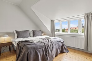 Une chambre à coucher avec un lit, une table de chevet, une lampe et une fenêtre avec des rideaux.