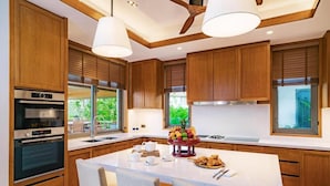 A modern kitchen with wooden cabinets, a central island with seating, and built-in appliances.