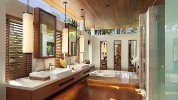 Un baño moderno con suelo de madera, lavamanos dobles y espejos grandes.