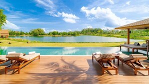 A poolside area with lounge chairs and a view of a lake.