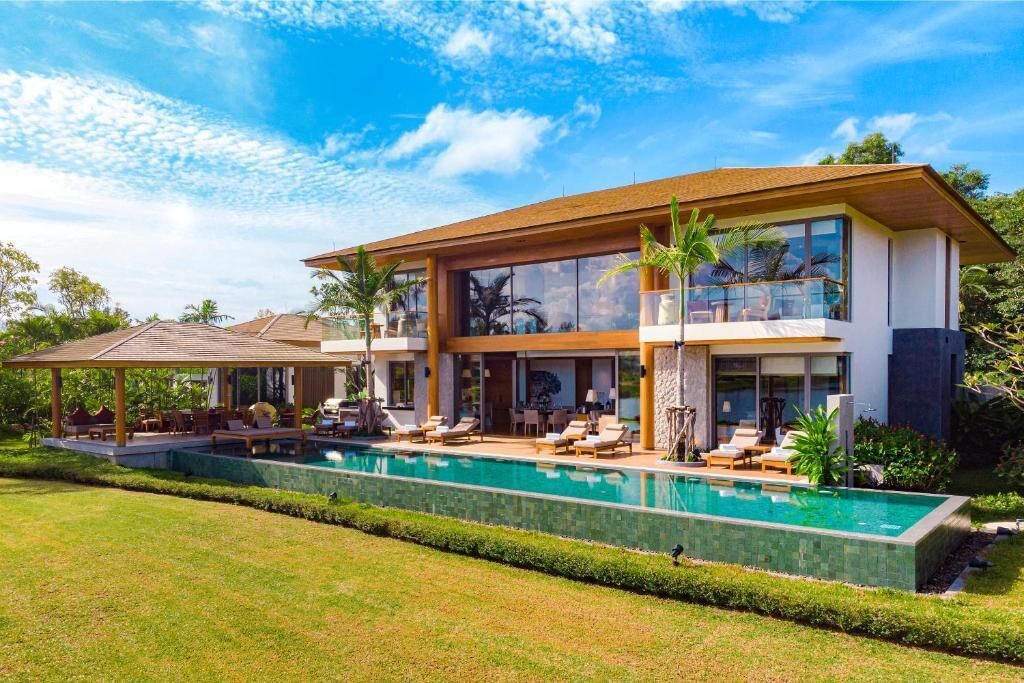 A modern two-story house with a swimming pool, outdoor seating, and a covered patio.