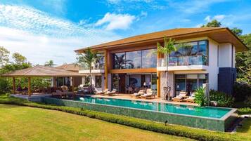 A modern two-story house with a swimming pool, outdoor seating, and a covered patio.