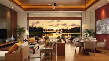 A modern living room with a large window overlooking a lake, furnished with sofas, chairs, and a dining area.
