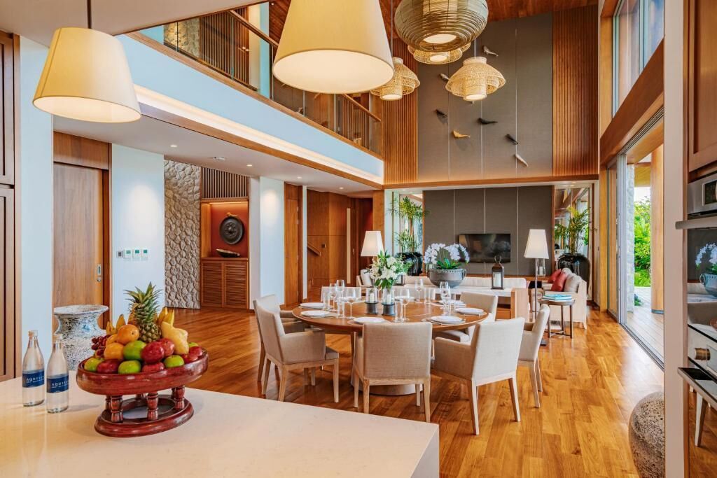 Un comedor espacioso con techo alto, suelo de madera y una mesa central dispuesta para comer.