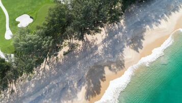 Un paisaje costero con una playa arenosa, un océano claro y un extenso bosque.