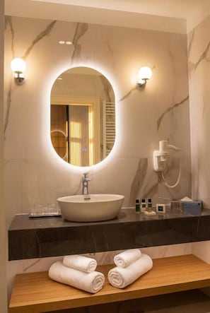 Un bagno con uno specchio tondo, un lavabo e due luci a parete.