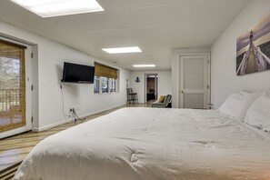 A hotel room with a large bed, a television mounted on the wall, and a painting of a bridge. - Pinnacle Lakefront Retreat: Dock, Canoe & Fire Pit (Pinnacle)