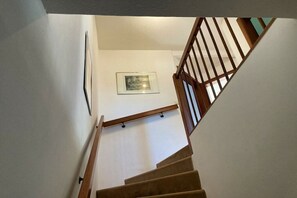 A staircase with wooden railings and a handrail, leading to a landing with a framed picture.
