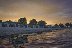 Una propiedad frente al mar con una hilera de edificios de estilo tradicional, una playa arenosa y una masa de agua tranquila.