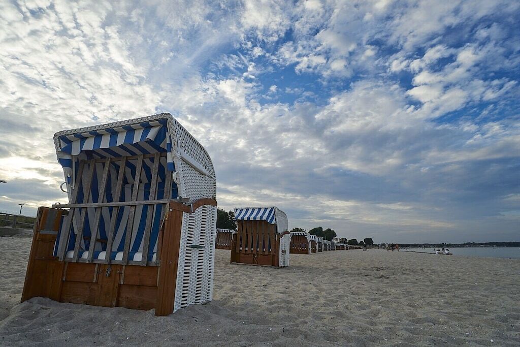 Ein Strand mit Reihen aus gestreiften Liegestühlen und Sonnenschirmen.