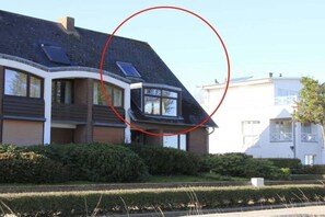 Un edificio residencial con techo inclinado, una ventana visible y un panel solar.