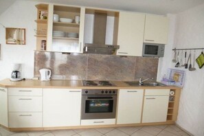 A compact kitchen with a built-in oven, microwave, and a coffee maker on the countertop. - Baltic Sea Dream Kronsgaard (Kronsgaard)