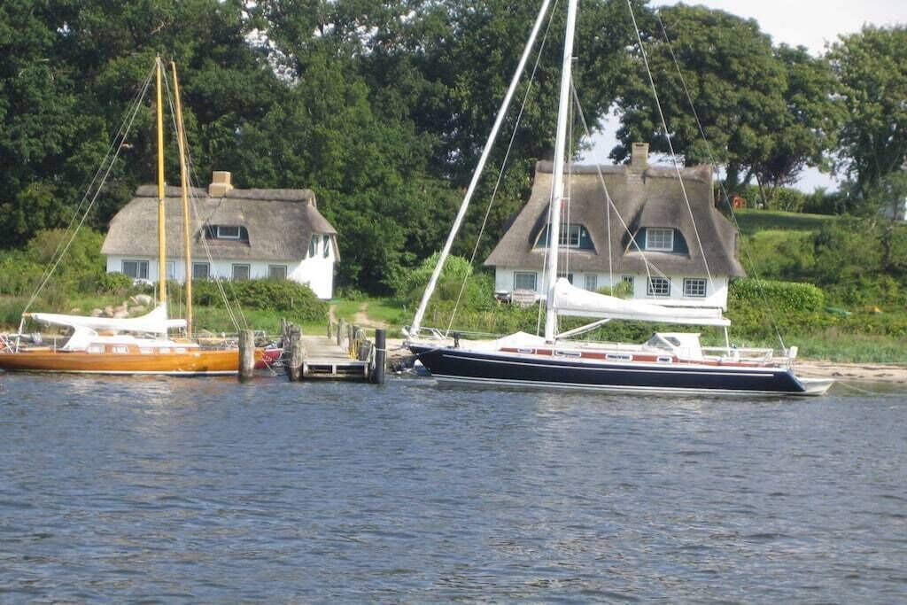 A calm waterway with two boats docked near houses with thatched roofs.
