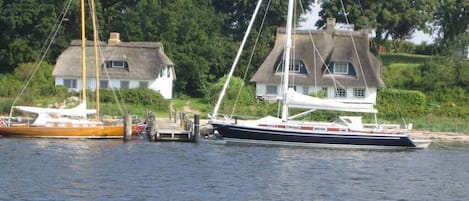 Una vía acuática tranquila con dos barcos amarrados cerca de casas con techos de paja.